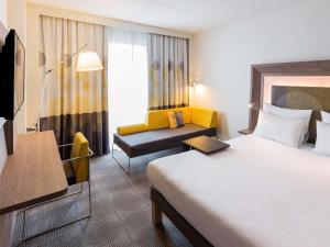 a hotel room with a bed and a couch at Novotel Amsterdam Schiphol Airport in Hoofddorp