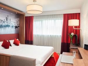a bedroom with a large white bed and a desk and a window at Aparthotel Adagio Birmingham City Centre in Birmingham