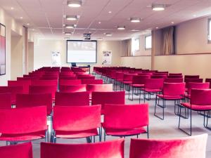 una sala de conferencias con sillas rojas y una pantalla en Mercure Maurepas Saint Quentin en Maurepas