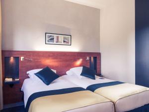 sypialnia z 2 łóżkami i białymi i niebieskimi poduszkami w obiekcie Mercure Maurepas Saint Quentin w mieście Maurepas