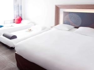 eine Reihe von Betten in einem Hotelzimmer in der Unterkunft Novotel Krasnoyarsk Center in Krasnojarsk