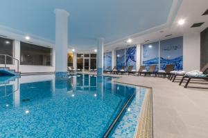 a large swimming pool in a building with chairs at Hotel Aqua in Abano Terme