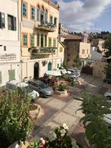 Blick auf eine Straße mit geparkten Autos und Gebäuden in der Unterkunft Al Bishara Guest House in Nazareth