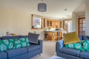 uma sala de estar com dois sofás azuis e uma cozinha em Broughty Ferry Apartment em Dundee