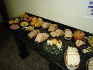 uma mesa com um monte de sanduíches e outros alimentos em Hotel Linhares em Itajaí