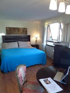 1 dormitorio con cama azul, mesa y silla en Costanera Center Apartment, en Santiago