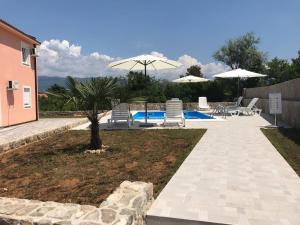 a patio with chairs and umbrellas next to a pool at Apartments Kuk in Šilo