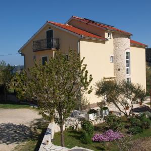 a house with a tree in front of it at Apartments Batistić in Supetarska Draga