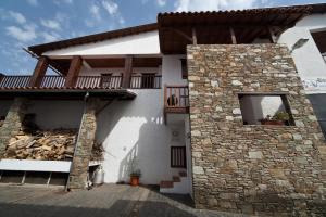 a white house with a stone wall and a balcony at A. Montesinho Turismo in Bragança
