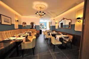 a restaurant with tables and chairs and a chandelier at Hotel Rheinischer Hof in Erkelenz
