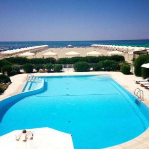 a large blue swimming pool with the ocean in the background at Villa La Bouganville Versilia in Marina di Pietrasanta