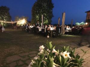 um grupo de pessoas sentadas em mesas em um parque à noite em Agriturismo Casa Rossa Ai Colli em Ragogna