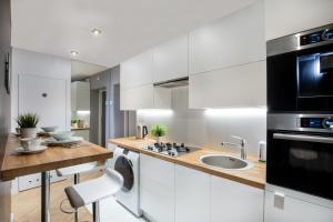 a kitchen with white cabinets and a sink and a microwave at Rainbow Apartments 3 in Krakow