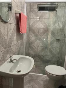 uma casa de banho com um lavatório, um WC e um espelho. em Hotel Linhares em Itajaí