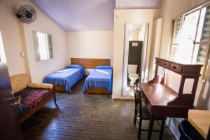 a room with two beds and a table and a desk at Hostel Casarão in Viçosa +75 photos