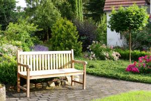 a wooden bench sitting in a garden with flowers at Landhotel Bauernwald in Faßberg