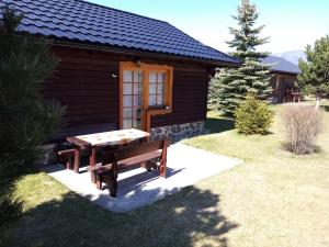 eine Holzhütte mit einem Picknicktisch davor in der Unterkunft Chata Lucia 112 in Liptovský Mikuláš
