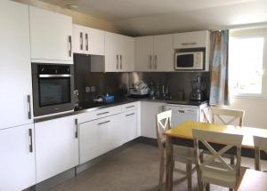 a kitchen with white cabinets and a table with chairs at Maison de vacances de 56 m2 dans résidence avec piscine chauffée proche plages in Locmaria