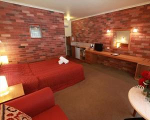 a hotel room with a red bed and a brick wall at Mansfield Valley Motor Inn in Mansfield