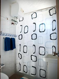 a bathroom with a shower curtain with a toilet and a sink at Apartamentos Oyster in Atlántida