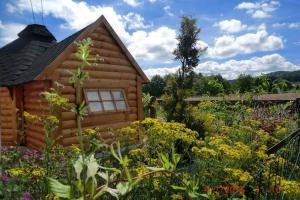 a log cabin with flowers in front of it at KOTA Finlandais bien être , les gîtes de l'étang in La Chapelle