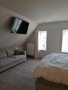 a bedroom with a bed and a couch and a flat screen tv at Vakantiewoning De Nachtegaal in Ostend