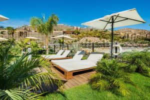 eine Gruppe von Stühlen und Sonnenschirmen auf einer Terrasse in der Unterkunft Anfi del Mar 2 in La Playa de Arguineguín