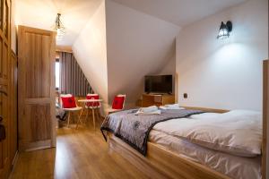 a bedroom with a bed and a tv and red chairs at Willa Pod Wierchami in Zakopane