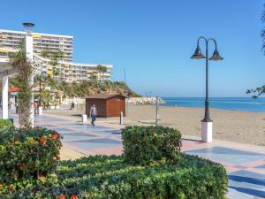 uma pessoa a caminhar numa praia com um poste de luz em Apartamentos LOLA y MANUELA en primera línea playa Carihuela con excelente Terraza-jardin de 80 m2 frente al Mar con aparcamiento privado Ideal para descansar oyendo las olas del Mar em Torremolinos