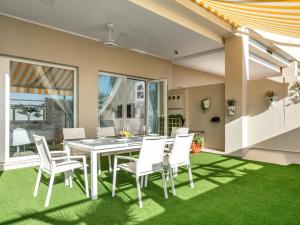 トレモリノスにあるApartamentos LOLA y MANUELA en primera línea playa Carihuela con excelente Terraza-jardin de 80 m2 frente al Mar con aparcamiento privado Ideal para descansar oyendo las olas del Marのテーブルと白い椅子のあるダイニングルーム