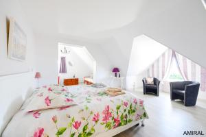 a bedroom with a bed with a floral bedspread and two chairs at Aux Premières Loges in Fécamp