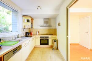a kitchen with white cabinets and a sink and a window at Aux Premières Loges in Fécamp