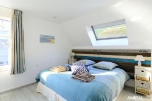 a bedroom with a bed with blue sheets and a window at Aux Premières Loges in Fécamp