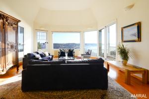 a living room with two black couches and large windows at Aux Premières Loges in Fécamp
