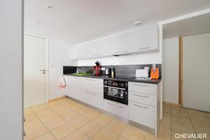 a kitchen with white cabinets and black appliances at Aux Premières Loges in Fécamp
