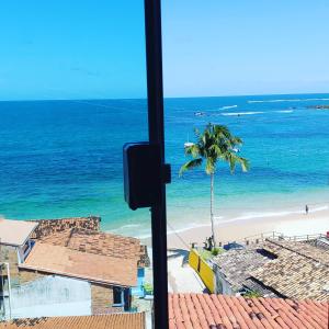 uma vista para uma praia com uma palmeira e o oceano em Flat Morro Pousada Casa Blanca em Morro de São Paulo
