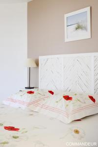 a white bedroom with a bed with red roses on it at Aux Premières Loges in Fécamp
