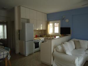a kitchen with a white couch and a white refrigerator at Plakes Suites in Skiathos