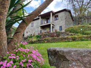 une maison en pierre avec des fleurs roses devant elle dans l'établissement Casa Rustica Isabel VT PO 00176, à San Jorge