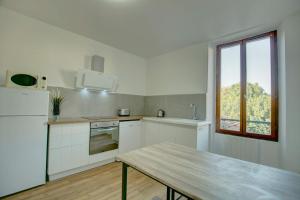 een witte keuken met een tafel en een raam bij Apart city in Montargis