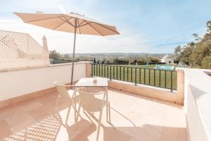 uma mesa e cadeiras numa varanda com um guarda-sol em Conimbriga Hotel do Paço em Condeixa a Nova