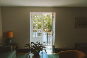 a living room with a glass table and a window at Conimbriga Hotel do Paço in Condeixa a Nova