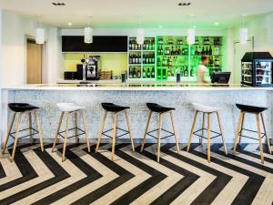 a bar with four stools in front of a counter at ibis Styles London Heathrow Airport in Hillingdon