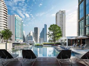 a pool with chairs and a city skyline at Novotel Bangkok Sukhumvit 20 in Bangkok