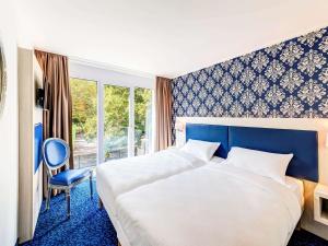 ein Hotelzimmer mit einem großen Bett und einem Stuhl in der Unterkunft ibis Styles Rastatt Baden-Baden in Rastatt