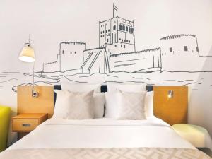 a bedroom with a bed with a drawing on the wall at Mercure Sohar in Sohar