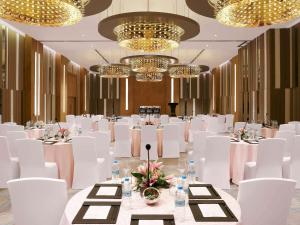 a banquet hall with white chairs and tables and chandeliers at Novotel Guwahati GS Road in Guwahati