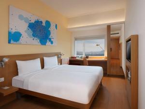 a bedroom with a large white bed and a window at ibis Pune Hinjewadi - An Accor Brand in Pune
