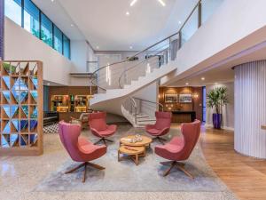 a lobby with chairs and a table and a staircase at Mercure Fortaleza Meireles in Fortaleza