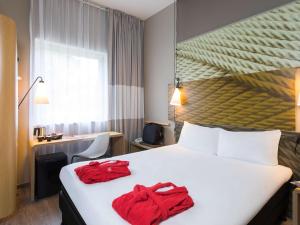 une chambre d'hôtel avec un lit et des serviettes rouges. dans l'établissement ibis De Haan, au Coq